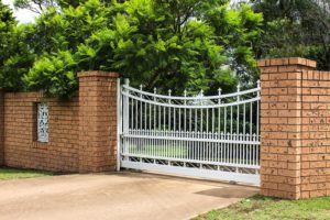 An automatic driveway gate framed by brick posts.