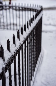 Iron fence with snow curving around corner